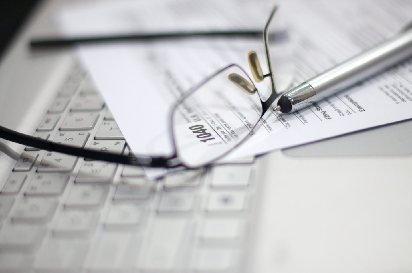 Eyeglasses and a silver pen resting on a tax form.
